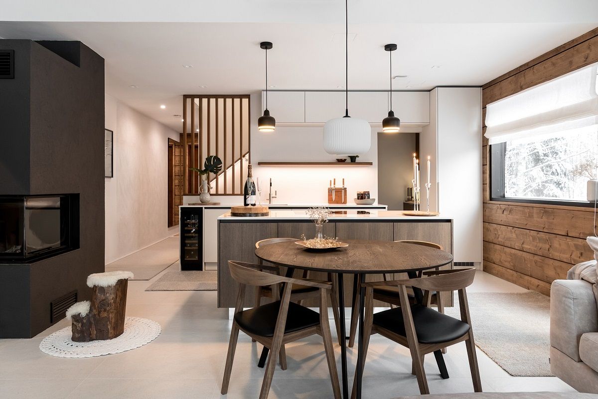 Illuminazione della cucina living con luci a sospensione sull'isola e sul tavolo da pranzo e striscia LED sul piano di lavoro